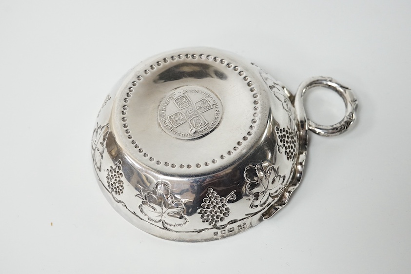 A George V silver taste vin, by Daniel & John Welby, with fruiting vine decoration and inset coin centre, London, 1924, diameter 92mm, 4.1oz. Condition - fair to good